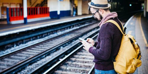 Man met telefoon wacht op de trein