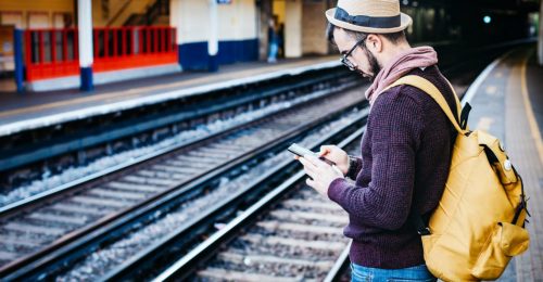 Man met telefoon wacht op de trein